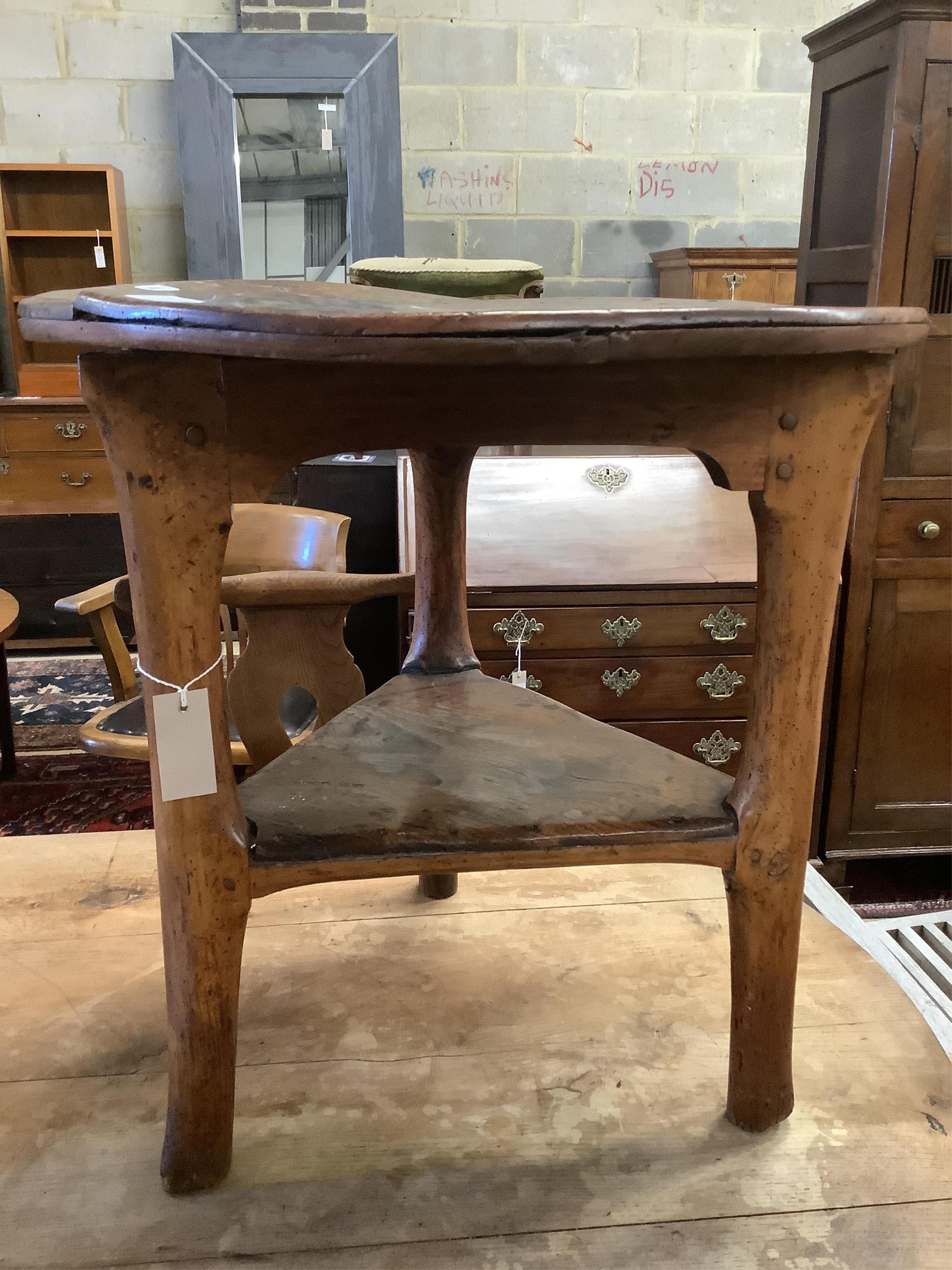 An 18th century elm cricket table, width 63cm, height 64cm. Condition - extensive splitting and old patches and repairs to the top, legs probably reduced, but full of character